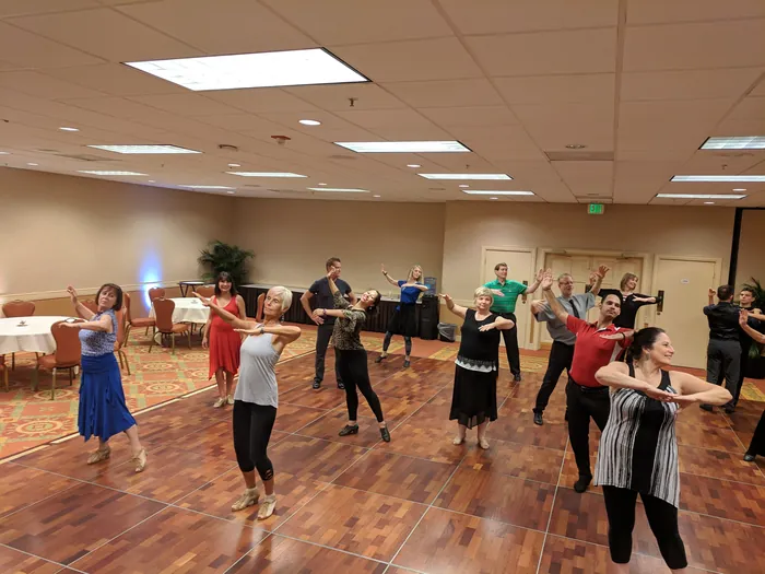Students across the floor with arms extended to the side, several turning mid-figure