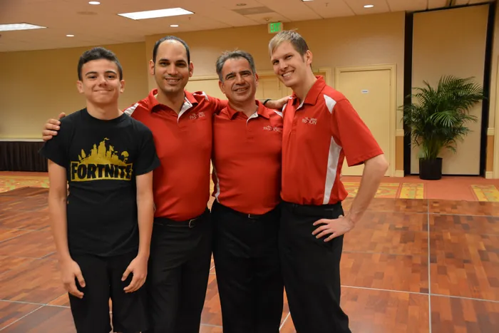 Victor, Carlos, Ivan and Bryan standing arm in arm, three of them in red Dance Passion polo shirts