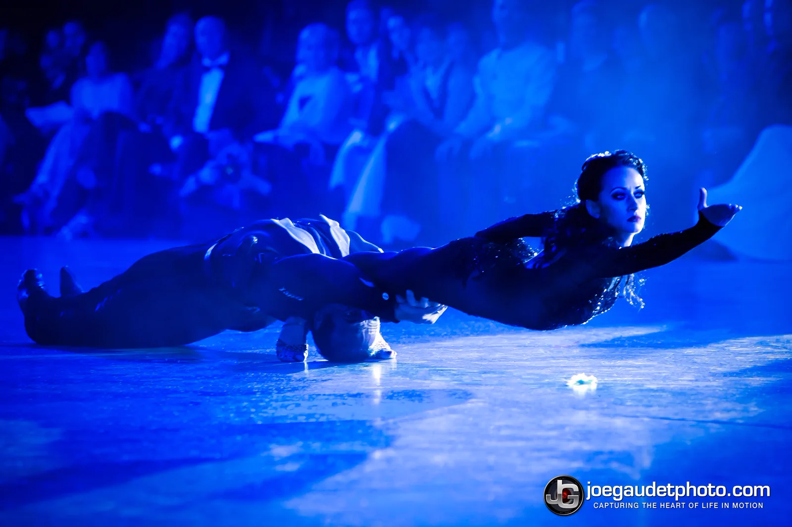 A couple in a deep oversway, lit from behind in blue