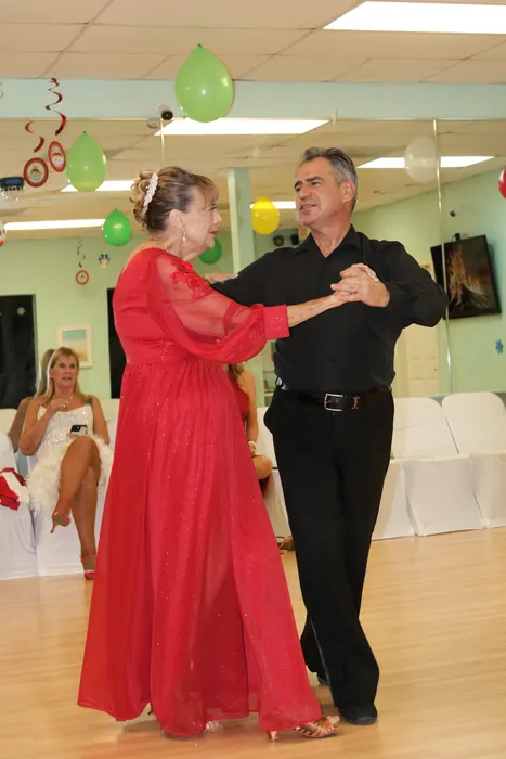 Eleanor in a long red dress dancing in a closed hold with Ivan