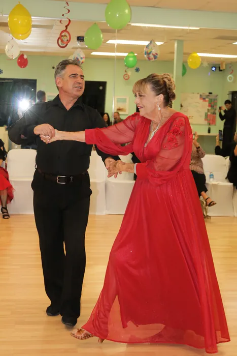 Eleanor's red gown sweeping wide as she reaches Ivan at arm's length