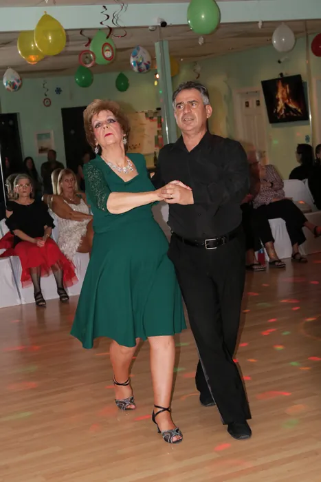 Lola in a green dress dancing in a closed hold with Ivan while guests watch