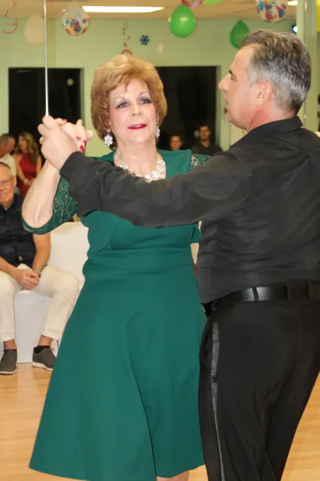 Lola in a green dress raising a joined hand with Ivan