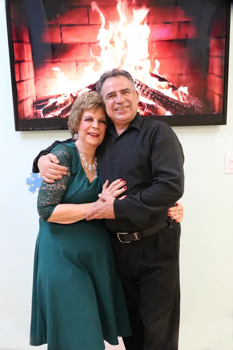Lola in a green dress posed with Ivan in front of the fireplace screen
