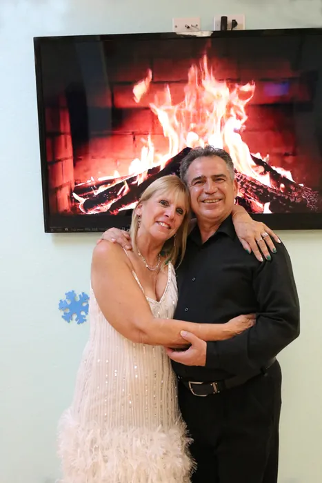 Peggie in a cream fringed dress posed with Ivan in front of the fireplace screen