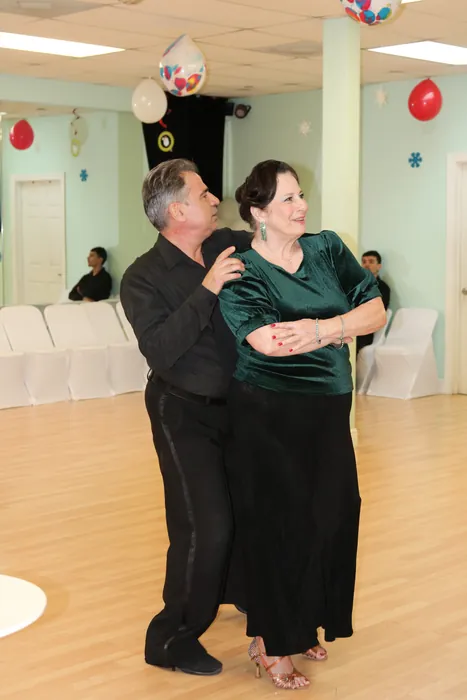 Sharon in a green velvet top and long black skirt dancing closely with Ivan