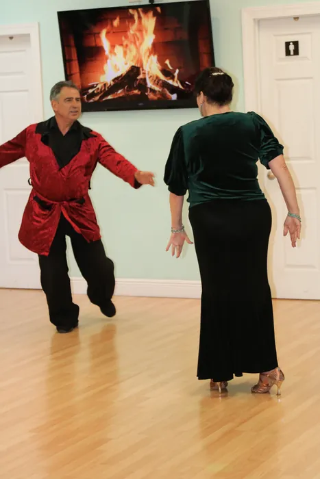 Sharon in a long black velvet gown turning away from Ivan in a red shirt