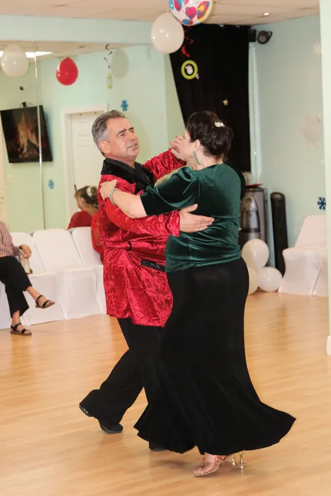 Sharon in green and black dancing with Ivan in a red patterned shirt