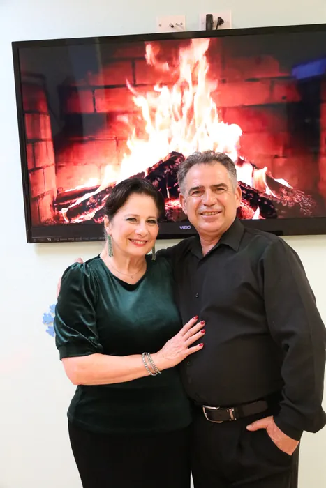 Sharon in green velvet posed with Ivan in front of the fireplace screen