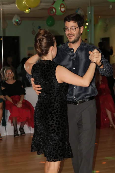 A couple in a close hold, her in a patterned black velvet dress