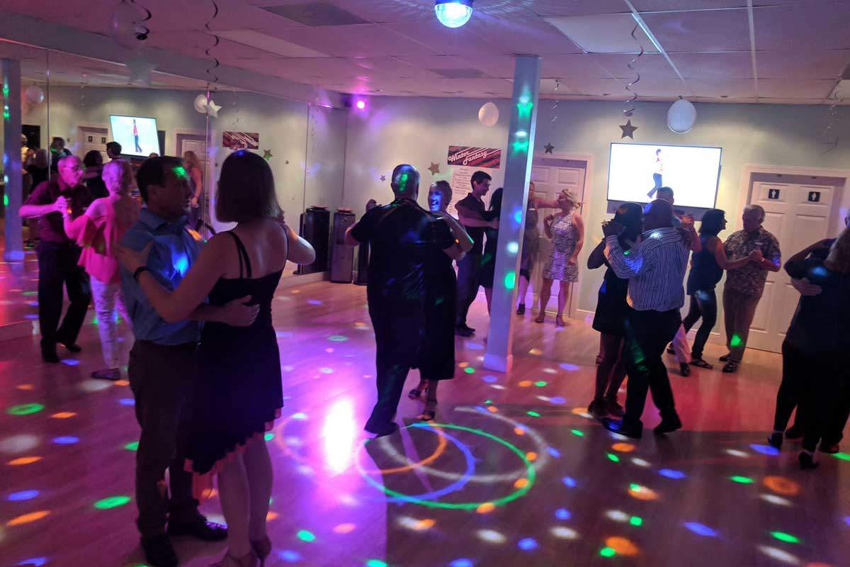 Couples dancing under party lights at a Dance Passion practice party