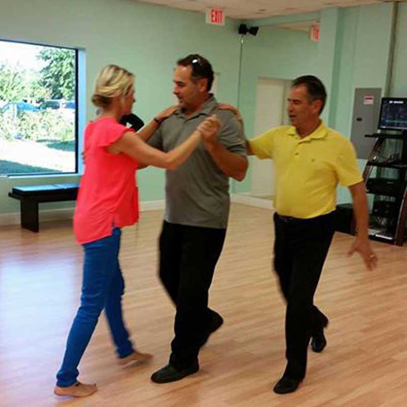 An instructor guiding two beginners through a step at the Dance Passion studio